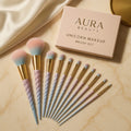 Unicorn makeup brush set with 'Aura Beauty' packaging on a beige surface