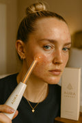 Aura Beauty High-Frequency Facial Wand with four glowing blue electrode attachments displayed on white marble background — luxury skincare device.