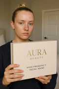 Aura Beauty High-Frequency Facial Wand with four glowing blue electrode attachments displayed on white marble background — luxury skincare device.